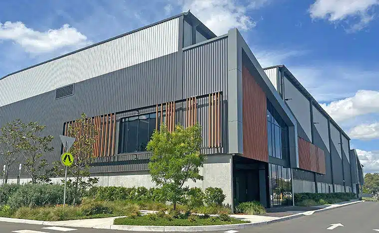 Corner of a modern warehouse unit complex with a foot path, garden and road